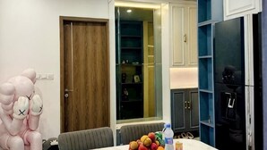 A room with a wooden door, a white wall, a blue cabinet, and a table with a water bottle. - X-Stay Luxe (Haiphong)