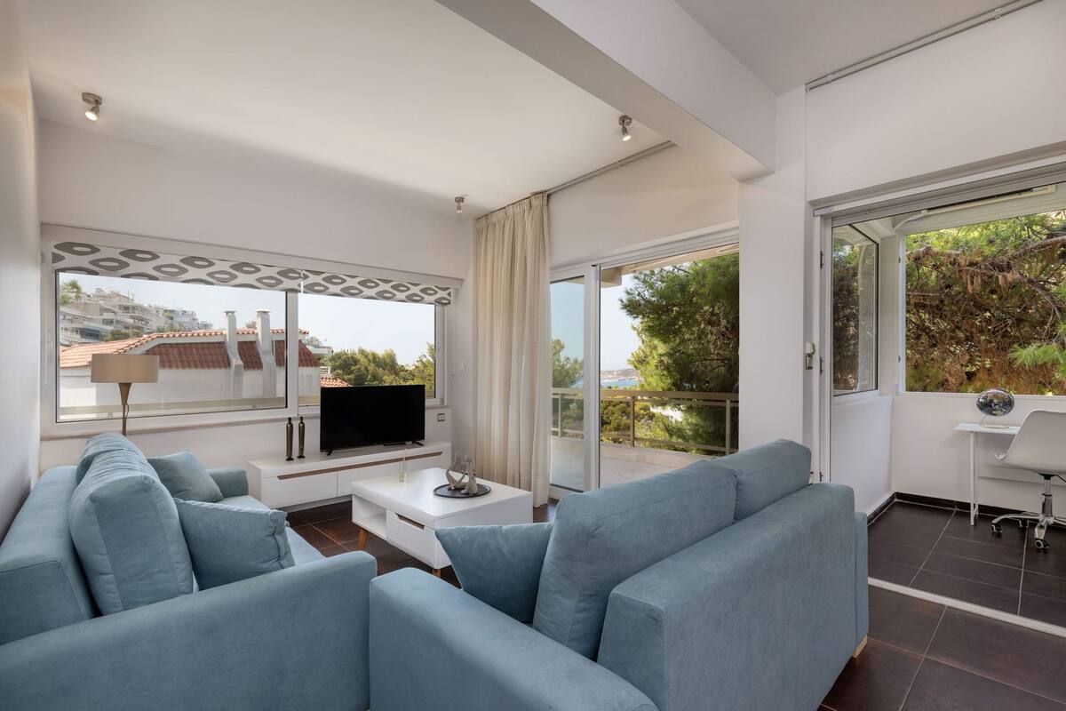 Una sala moderna con sofá, televisor y balcón con vistas.