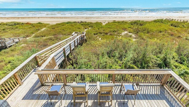 Una terraza de madera con sillas y una mesa con vista a la playa.