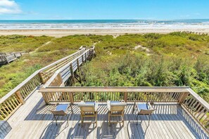 Una terraza de madera con sillas y una mesa con vista a la playa.