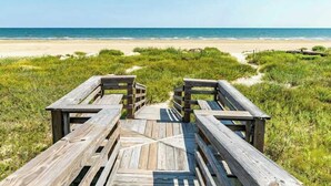 Una pasarela de madera que lleva a una playa, con vistas despejadas del océano.