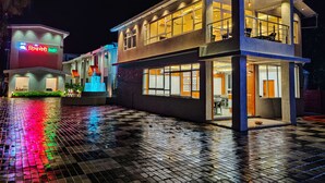 Um hotel de dois andares com design moderno, com grandes janelas e uma entrada bem iluminada.
