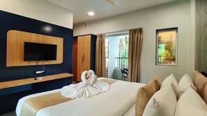 Quarto de hotel com cama, televisão na parede, ventoinha no teto e janela com cortinas.