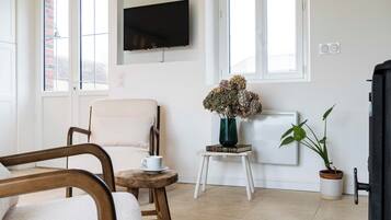 A modern living room with a sofa, armchair, and a small table with a vase of flowers.