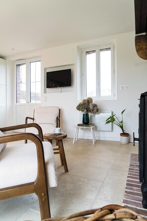 Een moderne woonkamer met een bank, fauteuil en een bijzettafeltje met een bloevas.
