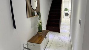 A hallway with a wooden counter, a mirror, a potted plant, a staircase, and a washing machine in the background. - M B Homes Worker House Lauterstein 8 Wi-Fi (Lauterstein)