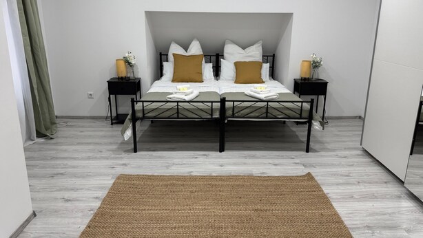 A bedroom with a bed, two nightstands, a woven rug, and a green curtain. - M B Homes Worker House Lauterstein 8 Wi-Fi (Lauterstein)
