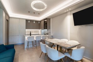 A modern kitchen with a marble countertop, white bar stools, and a dining table with chairs. - Apartment 'Villa Preziosa in Tirrenia' with Private Terrace, Wi-Fi and Air Conditioning (Tirrenia)