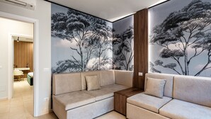 A modern living room with a beige sectional sofa, a wooden side table, and a large wall mural of trees.