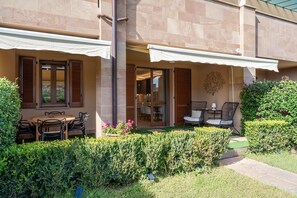 A patio with a table and chairs, a covered seating area, and a hedge. - Apartment 'Villa Preziosa in Tirrenia' with Private Terrace, Wi-Fi and Air Conditioning (Tirrenia)