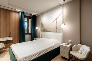 A bedroom with a bed, bedside tables, a desk, a chair, and a hanging light fixture. - Apartment 'Villa Preziosa in Tirrenia' with Private Terrace, Wi-Fi and Air Conditioning (Tirrenia)