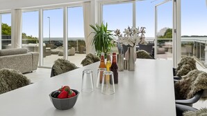 Un comedor moderno con una mesa blanca, cristalería transparente y un bol de fresas.