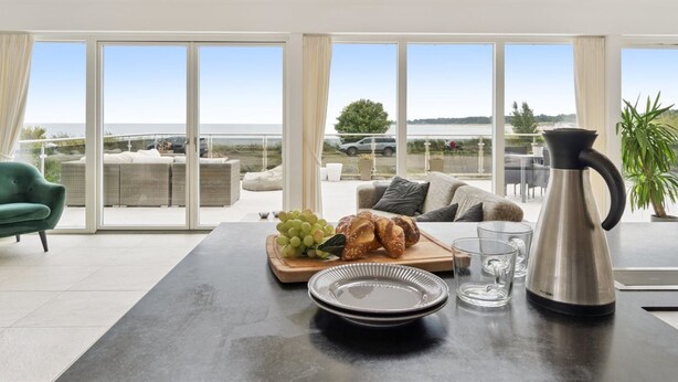 Una sala de estar moderna con comedor, ventanas amplias y vistas al exterior.