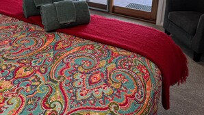 A hotel room with a large bed, a red throw blanket, and a view of a grassy area through a sliding glass door. - Poona Farm Estate - The Lodge (Coulta)