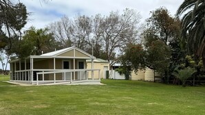 A single-story house with a covered porch and a fenced yard. - Poona Farm Estate - The Lodge (Coulta)
