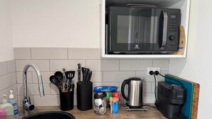 A kitchen with a stainless steel sink, a black countertop, a microwave, a coffee maker, and a knife block. - Poona Farm Estate - The Lodge (Coulta)