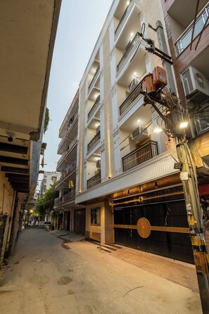 Een meerhoog gebouw met balkons, een overdekte ingang en een straat ervoor.