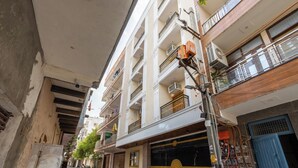 Edifício residencial de vários andares com varandas, entrada com portão e infraestrutura elétrica aparente.