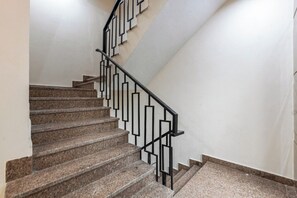 Una escalera con escalones de granito y barandilla de metal negro.