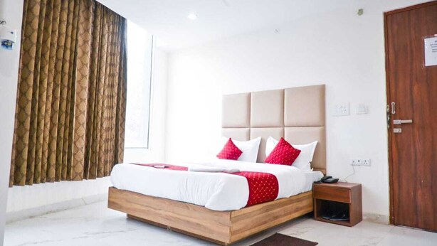A modern bedroom with a large bed, wooden headboard, and a nightstand. - Hotel Yashobhoomi Inn (New Delhi)