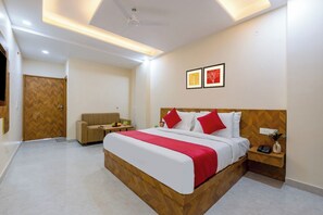 Una habitación de hotel con cama, mesita de noche y sofá.