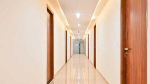 A long, well-lit hallway with wooden doors on both sides, leading to a bright room at the end. - Hotel Yashobhoomi Inn (New Delhi)