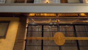 Hotel de vários andares com varandas, uma coluna central e entrada protegida por grades.
