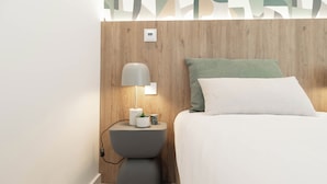 A modern bedroom with a wooden headboard, a bedside table with a lamp, a small plant, and a white bedspread. - Belemia Green Villa, Sintra, Lisbon (São João das Lampas)