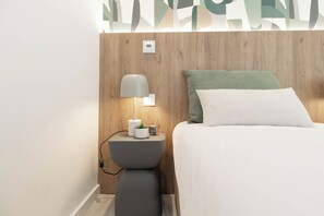A modern bedroom with a wooden headboard, a bedside table with a lamp, a small plant, and a white bedspread. - Belemia Green Villa, Sintra, Lisbon (São João das Lampas)