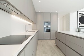 A modern kitchen with a built-in oven, a stainless steel range hood, and a sleek countertop. - Belemia Green Villa, Sintra, Lisbon (São João das Lampas)