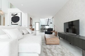 A modern living room with a white sofa, a wooden coffee table, and a large flat-screen TV. - Belemia Green Villa, Sintra, Lisbon (São João das Lampas)