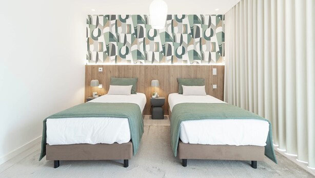 A modern bedroom with two beds, a wooden headboard, a geometric wall decoration, and a large window with curtains. - Belemia Green Villa, Sintra, Lisbon (São João das Lampas)