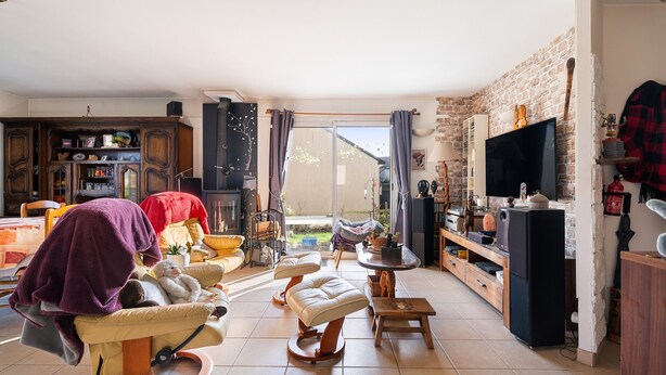 A living room with a sofa, ottoman, TV, and a fireplace.