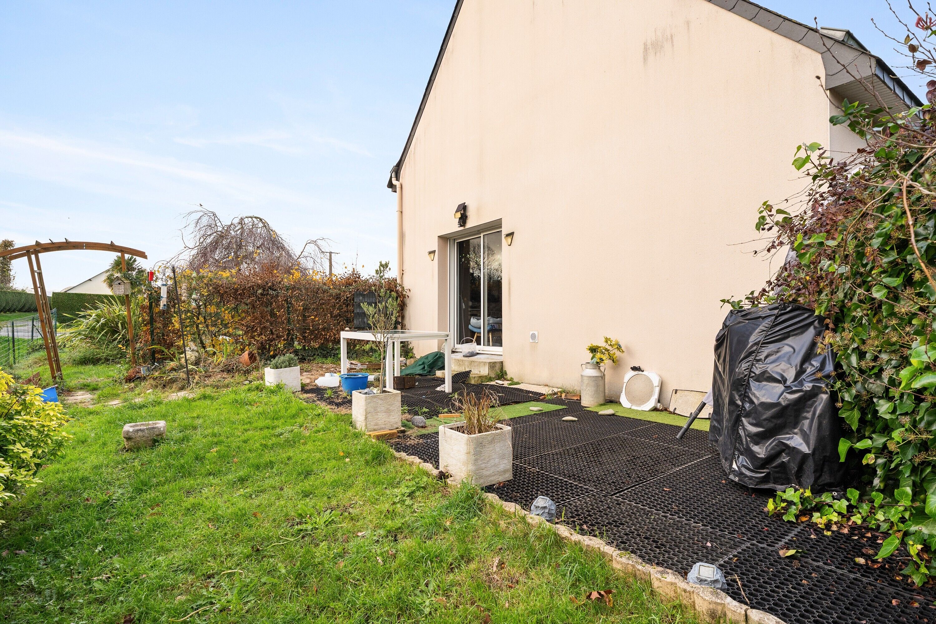 A house with a garden, a black mat outside, and a white door.