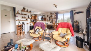 A living room with two rocking chairs, a fireplace, and a kitchen area with shelves.