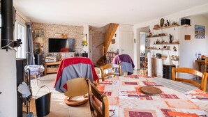 A cozy living room with a fireplace, a television, and a dining area with chairs and a table.