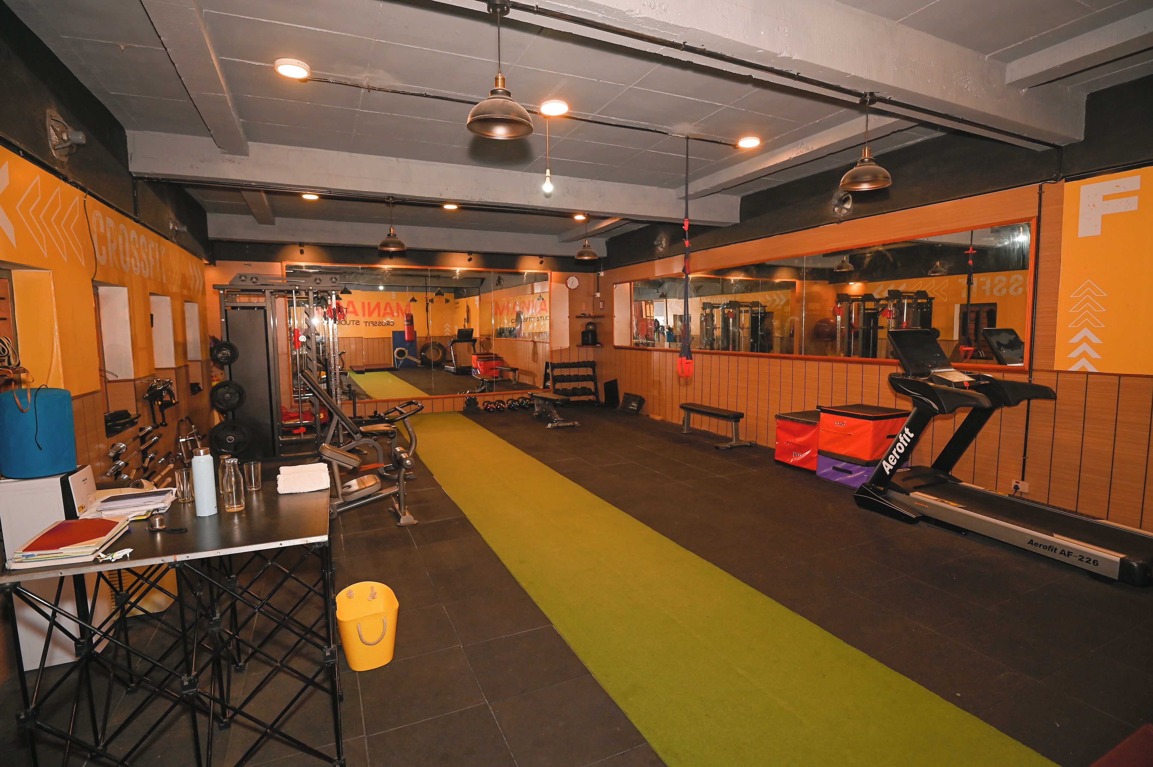 A gym with exercise equipment, a treadmill, and a mirrored wall.
