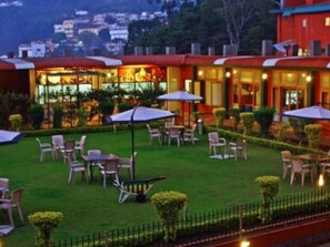 A hotel with outdoor seating and a view of the surrounding area. - Hotel Vivek (Coonoor)