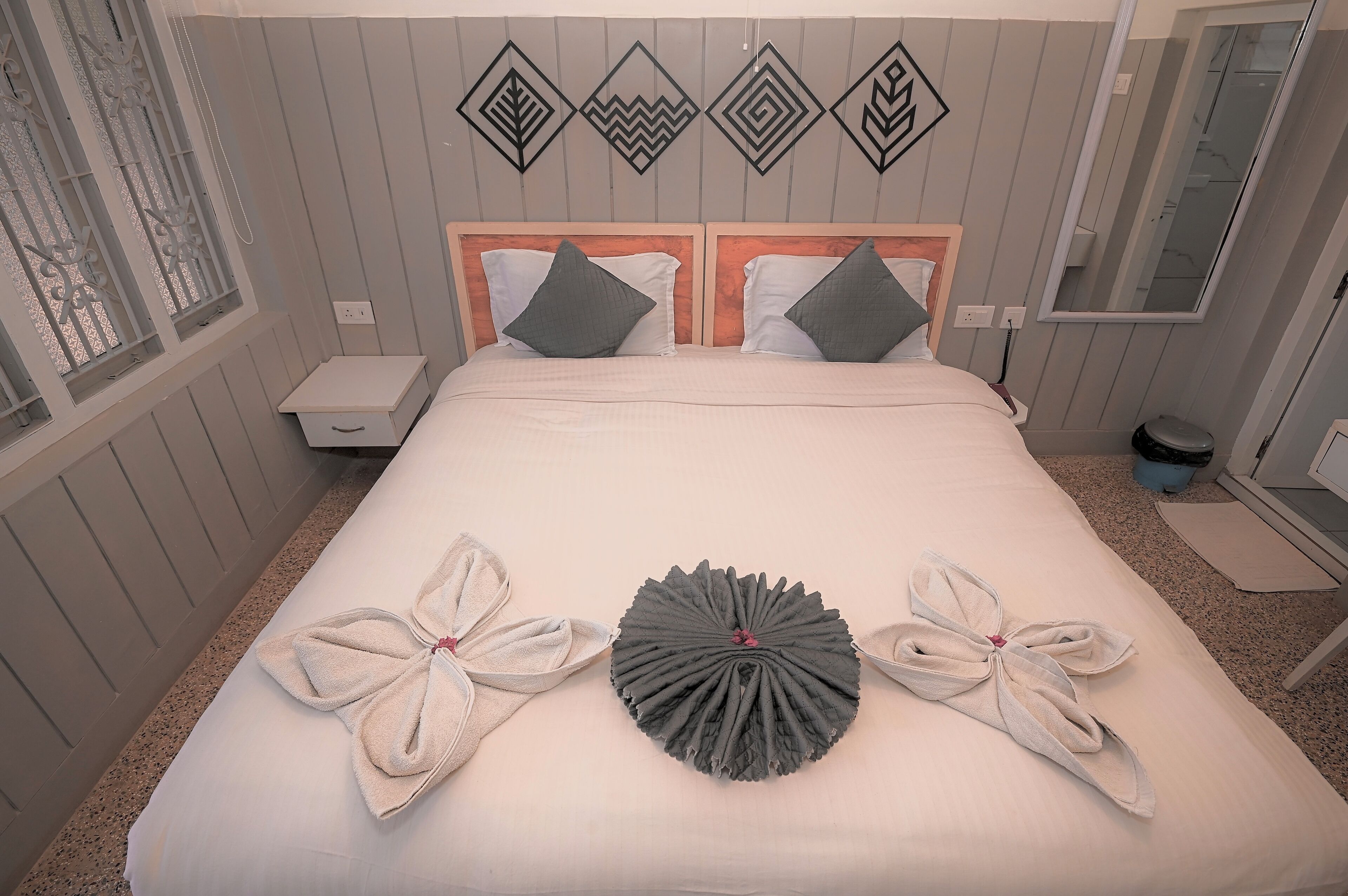 A neatly made bed with towels and a decorative headboard.