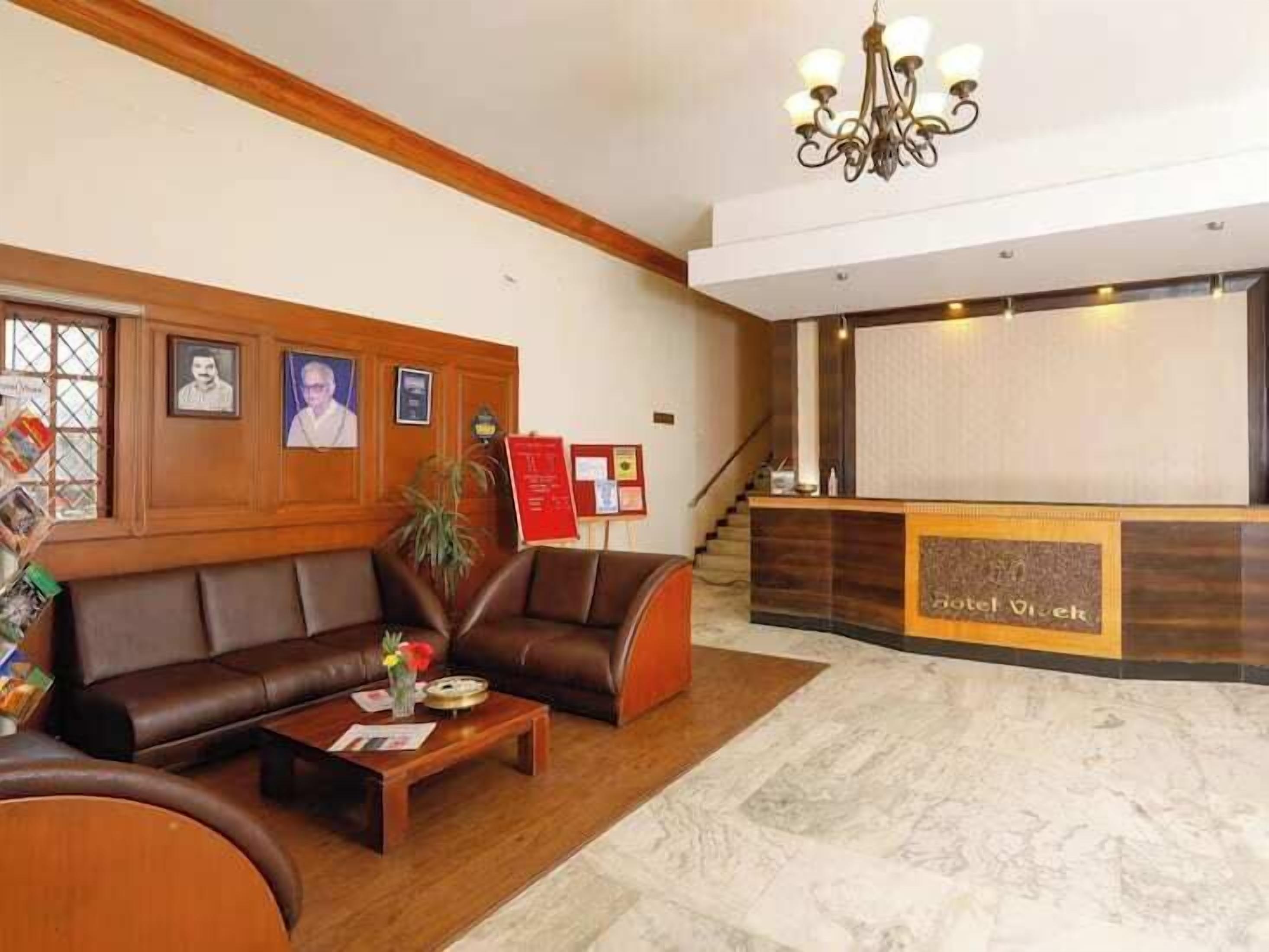 A hotel lobby with a reception desk, a leather sofa, a coffee table, and framed pictures on the wall.