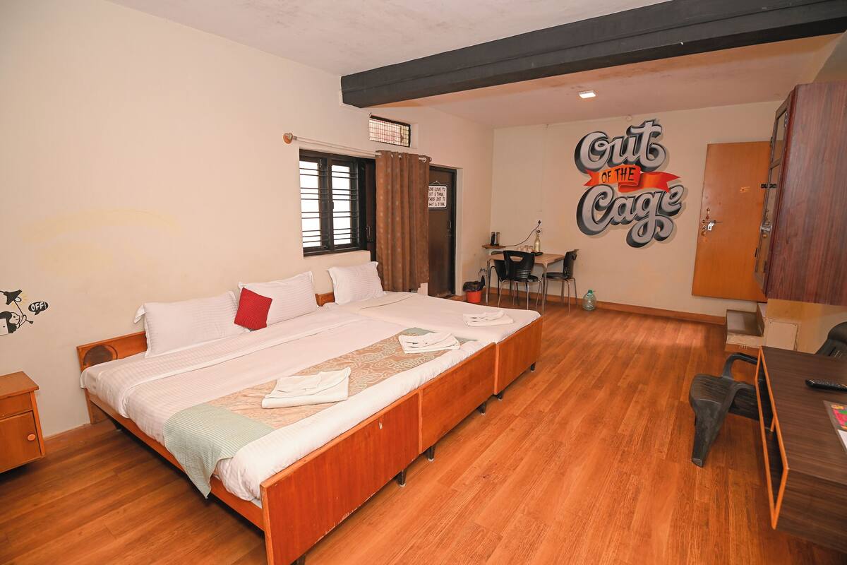 A bedroom with a large bed, a desk, and a chair. There is a sign on the wall that reads "Crit of the Cage".