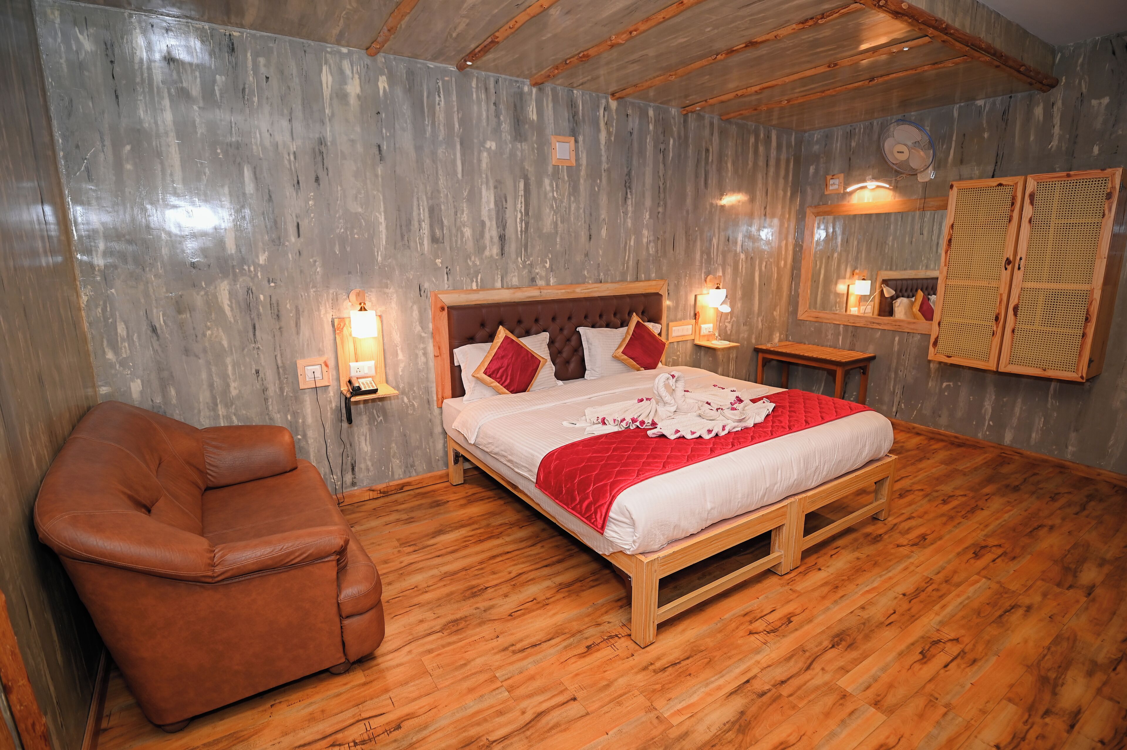 A bedroom with a wooden bed, a leather chair, and a wooden floor.