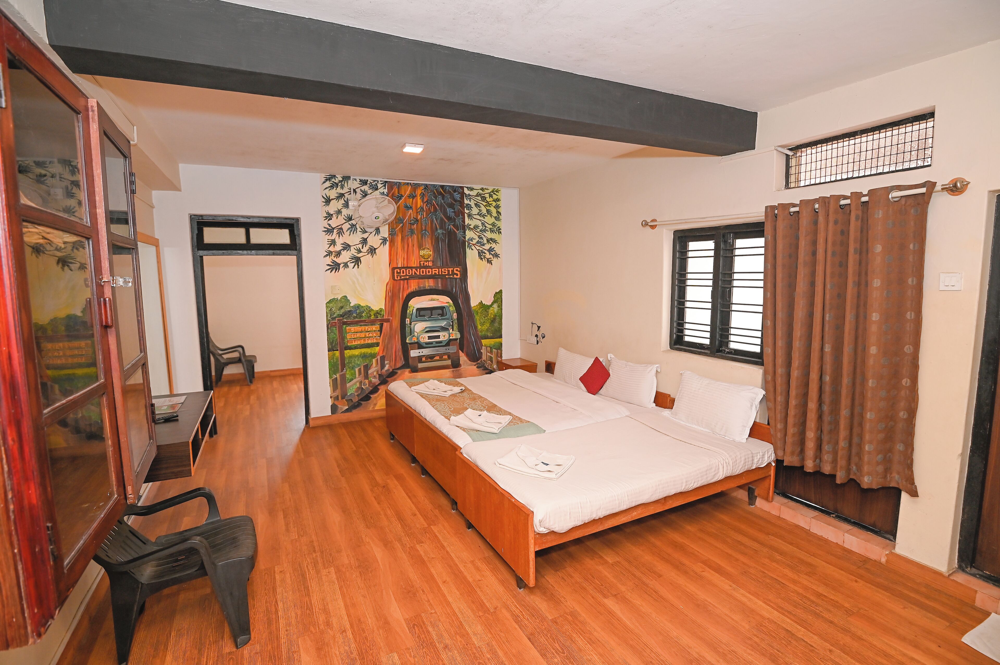A bedroom with a wooden bed, a desk, and a mural on the wall.