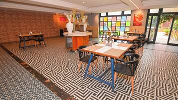 A hotel lobby with a patterned floor, a reception desk with vases, and a view of the outside.