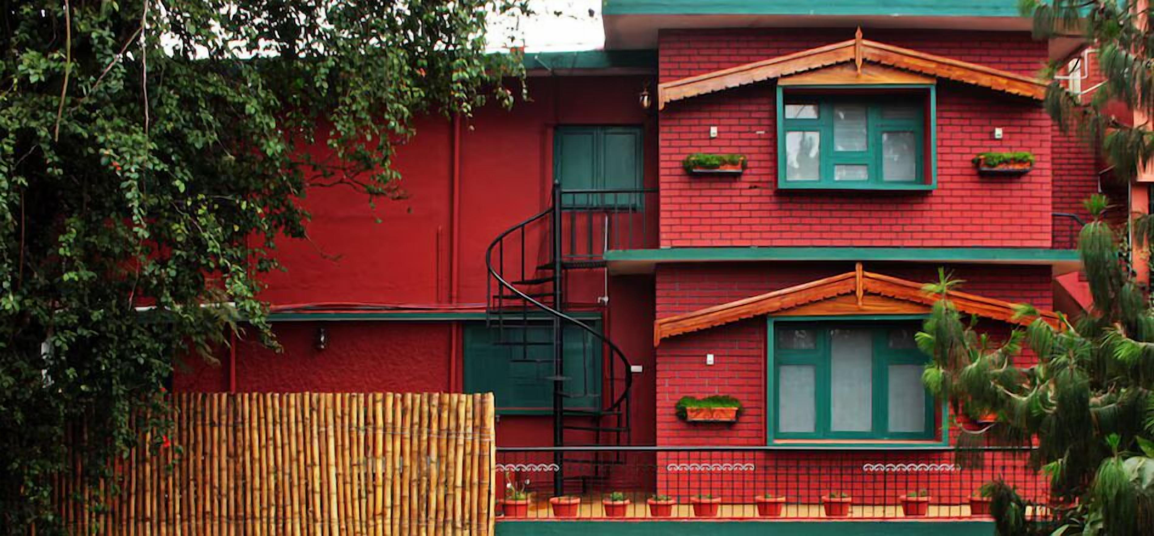 Ein rotes Gebäude mit zwei Fenstern, einer Wendeltreppe und Blumenkübeln am Balkon.