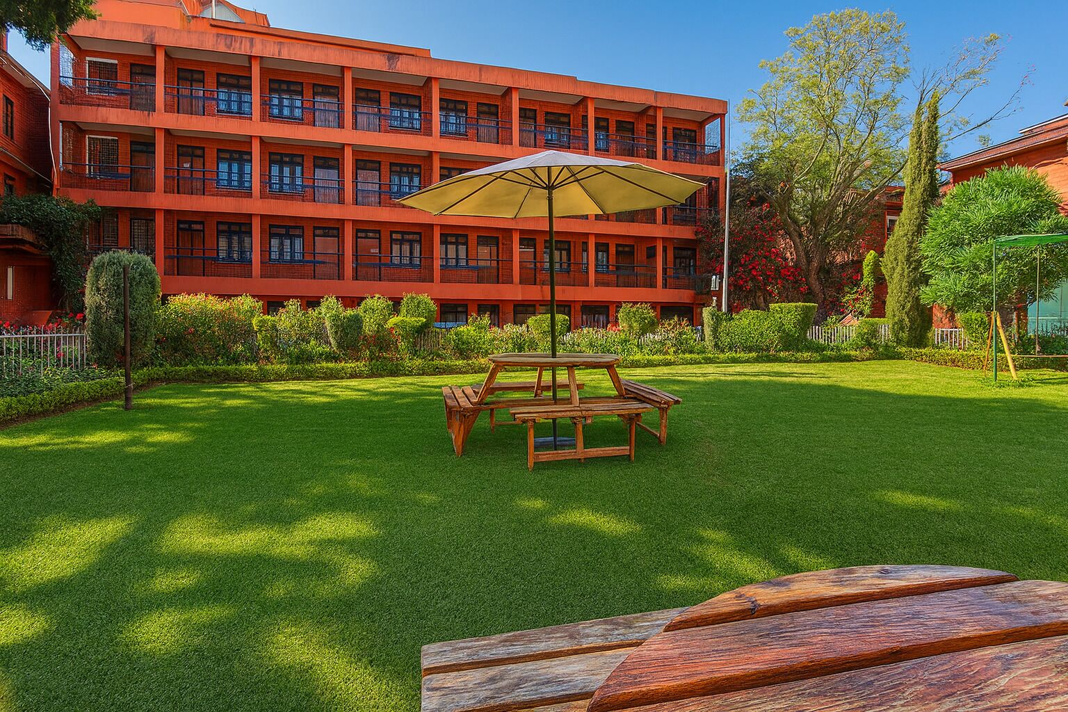 A red multi-story building with a well-maintained lawn and picnic tables.