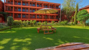 A red multi-story building with a well-maintained lawn and picnic tables.