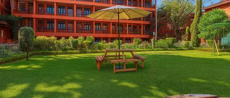 A red multi-story building with a well-maintained lawn and picnic tables.