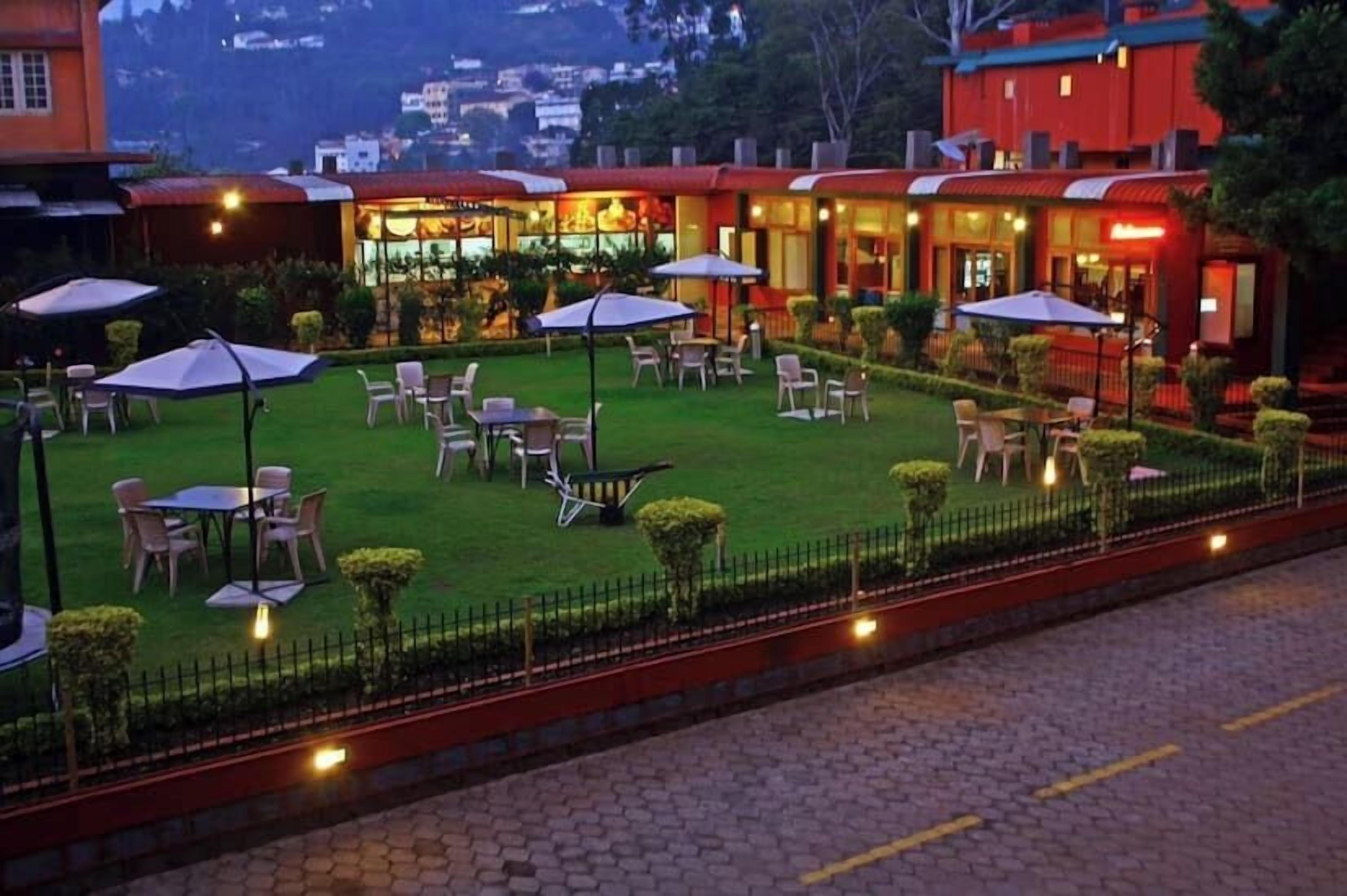 A hotel courtyard with outdoor seating, a well-maintained lawn, and a fence.