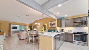A modern kitchen with a central island, stainless steel appliances, and a dining area with a chandelier. - HOT TUB & POOL TABLE The Coconut Lounge - Newly Renovated 3/2 in The Village of DeSoto (DeSoto, The Villages)